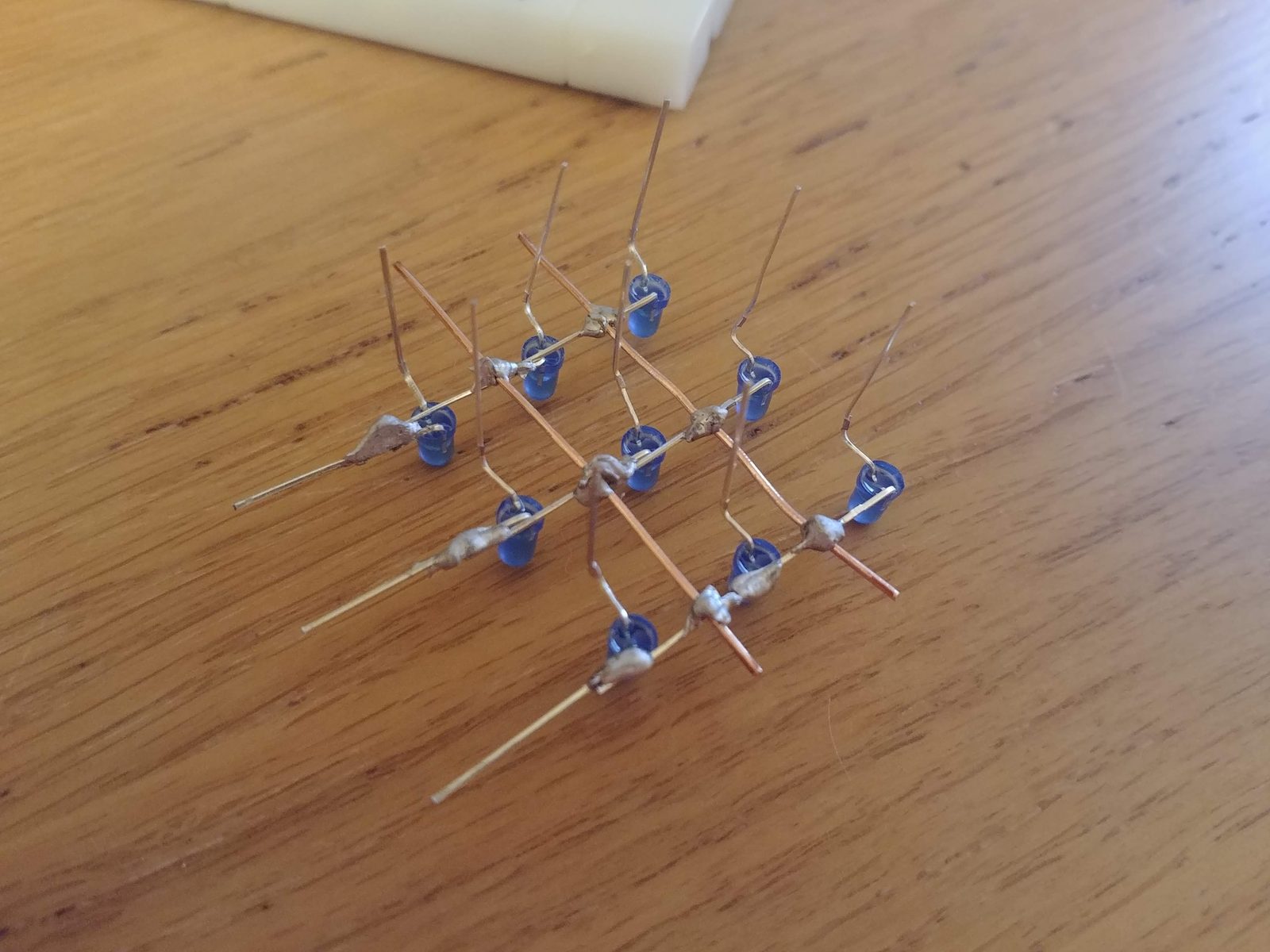A single soldered layer of nine blue LEDs on the cardboard jig