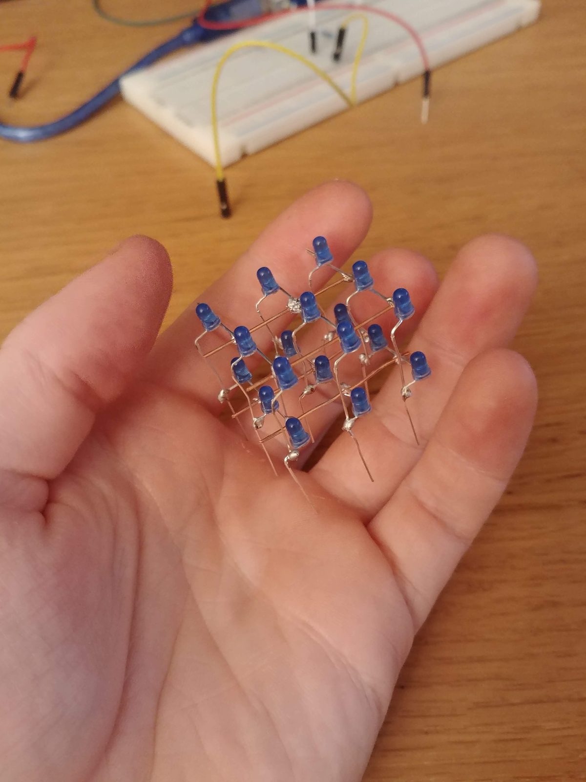 The finished 3×3×3 LED cube held in the palm of a hand