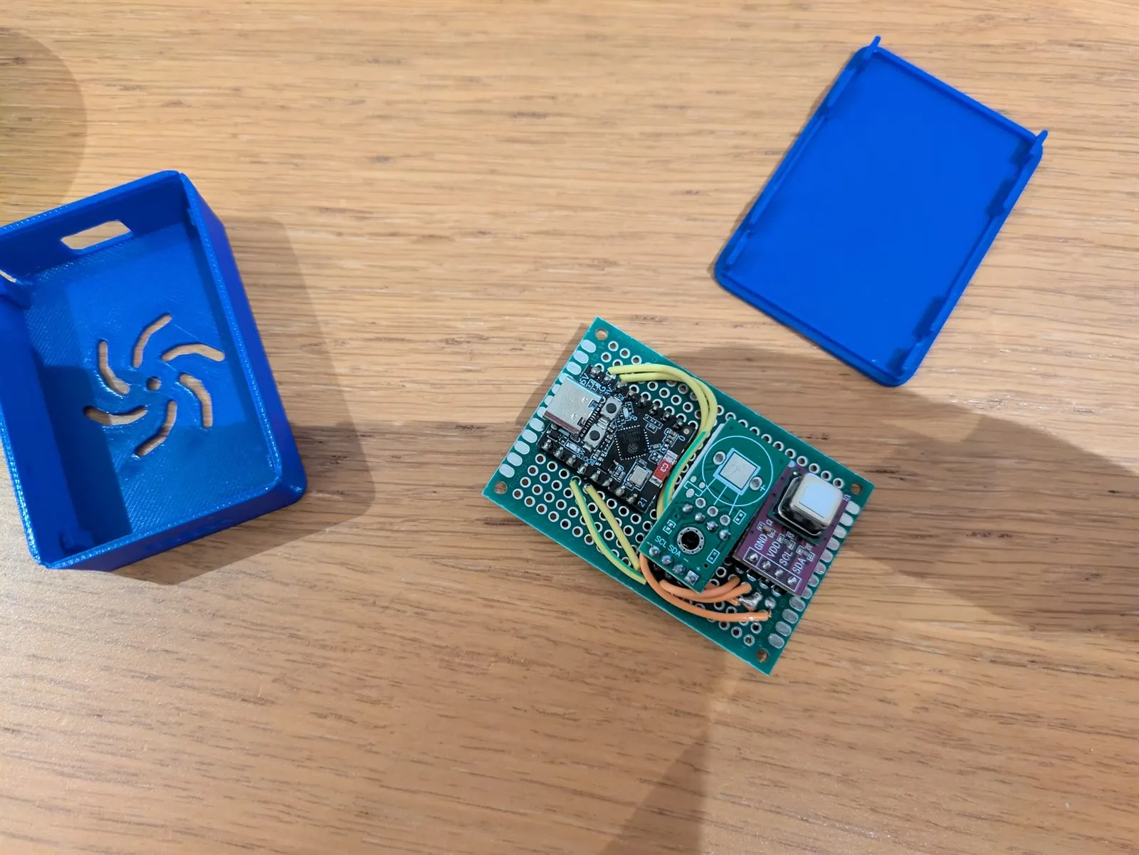Three sensor modules on a green perfboard beside an early blue case