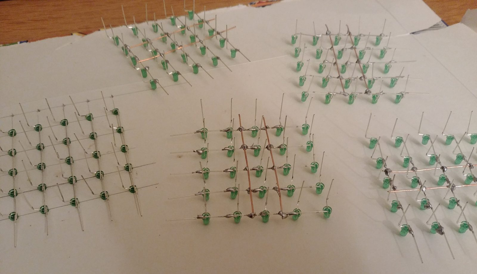 Several soldered rows of green LEDs laid out on paper before being joined